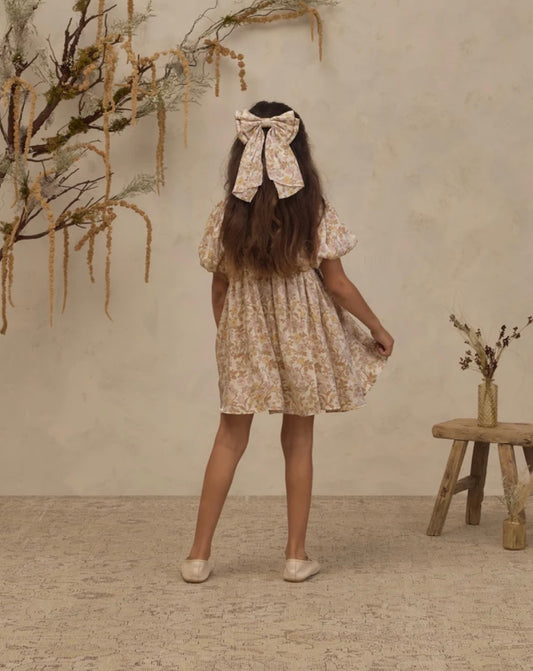 Back view of Noralee girls shimmering Luna dress with wildflower print and a bow detail on the back.