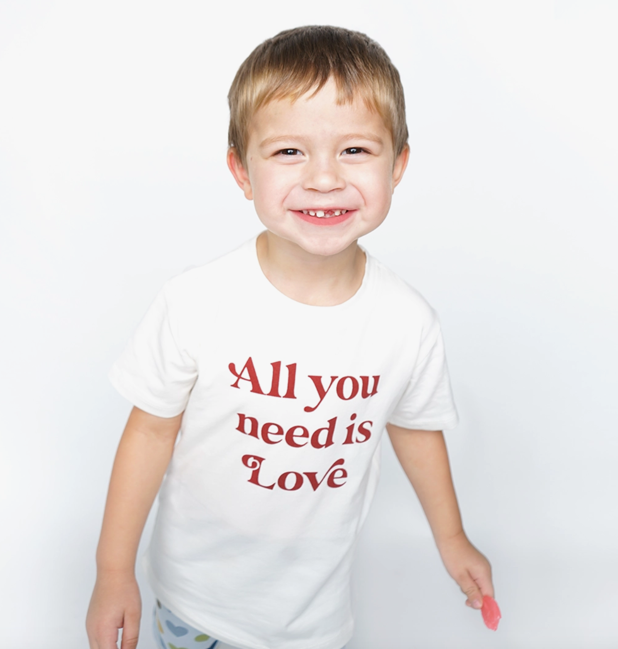 Emerson and Friends "All You Need Is Love" white cotton t-shirt with colorful text design, casual fit, and short sleeves.