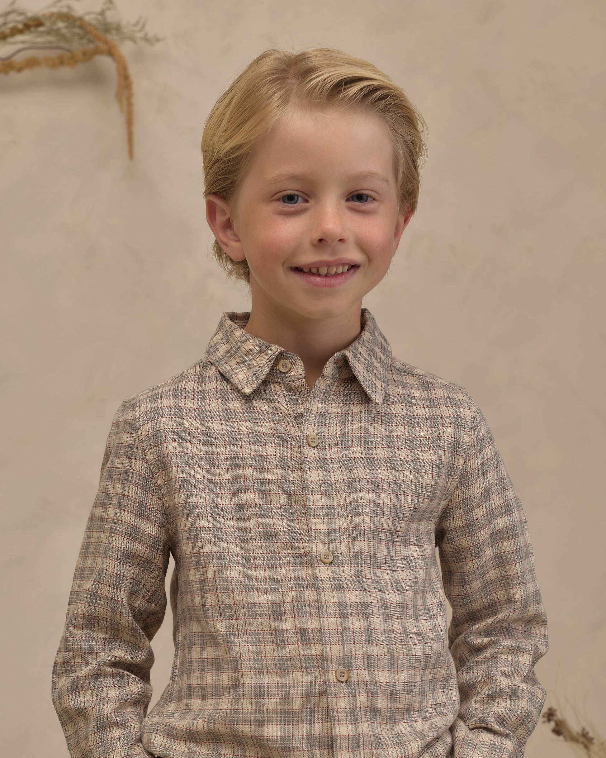 Boy wearing Noralee Harrison plaid button-down shirt with blue and green patterns, standing outdoors.