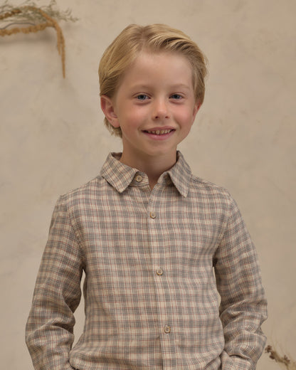 Boy wearing Noralee Harrison plaid button-down shirt with blue and green patterns, standing outdoors.