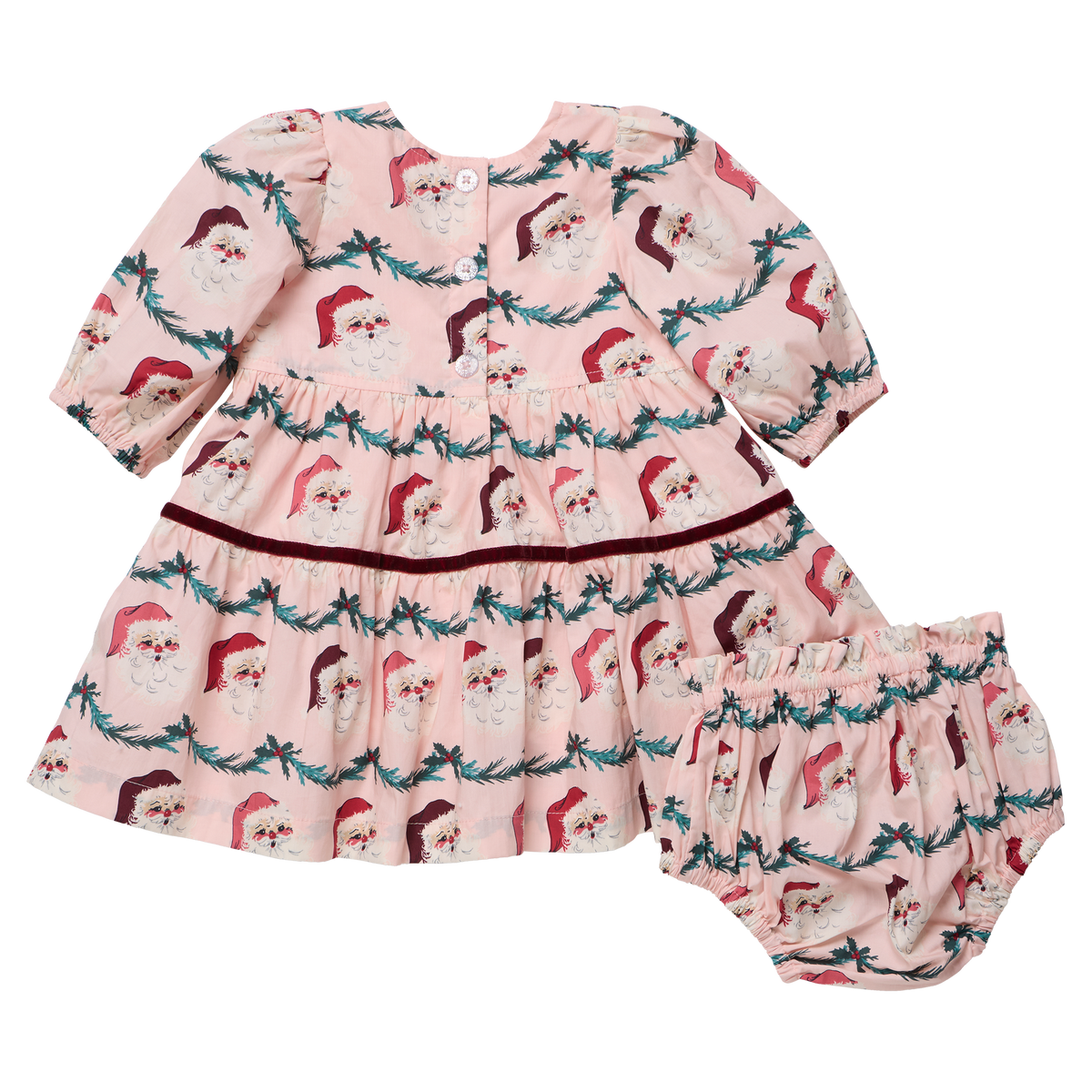 Baby girl wearing Pink Chicken Maribelle dress with Santa-themed garland, festive holiday outfit for young children.