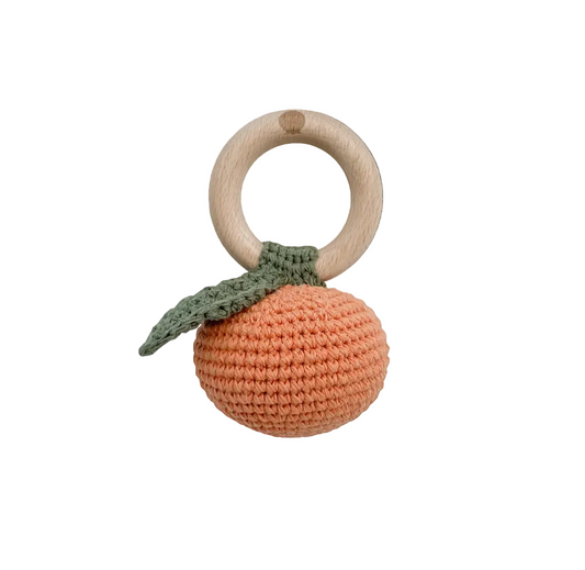Crochete orange-shaped teething ring with a wooden ring on a light gray background