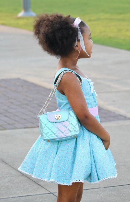 Girls Paige Bag in aqua metallic by Carrying Kind, showing a shiny, teal-colored kids' handbag with a sleek design.