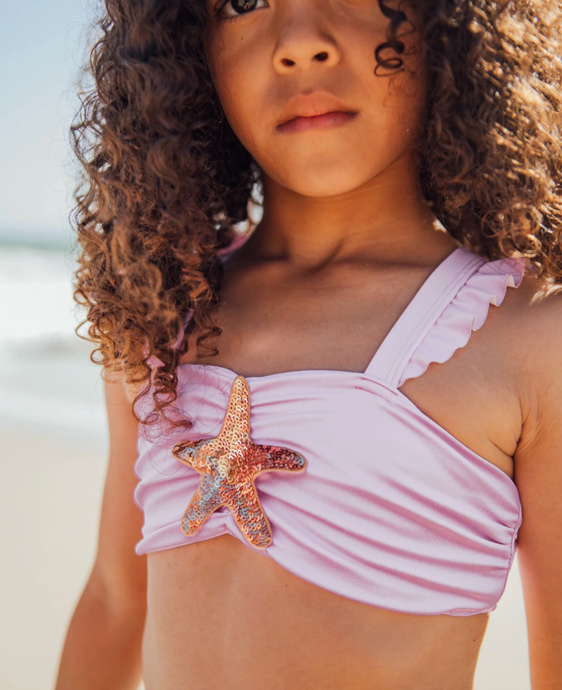 Girls Sea Star bikini by Feather 4 Arrow featuring a colorful starfish print and ruffled bikini top and bottom.