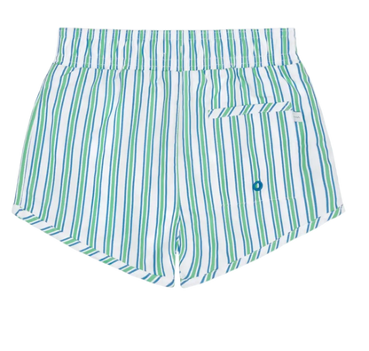 Boy wearing Minnow Tamarin Stripe boardie with blue and white stripes, standing on the beach in sunny weather.