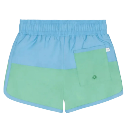 Boy wearing Minnow Island Edge colorblock boardie swim trunks with blue and orange panels, sitting on a sandy beach.