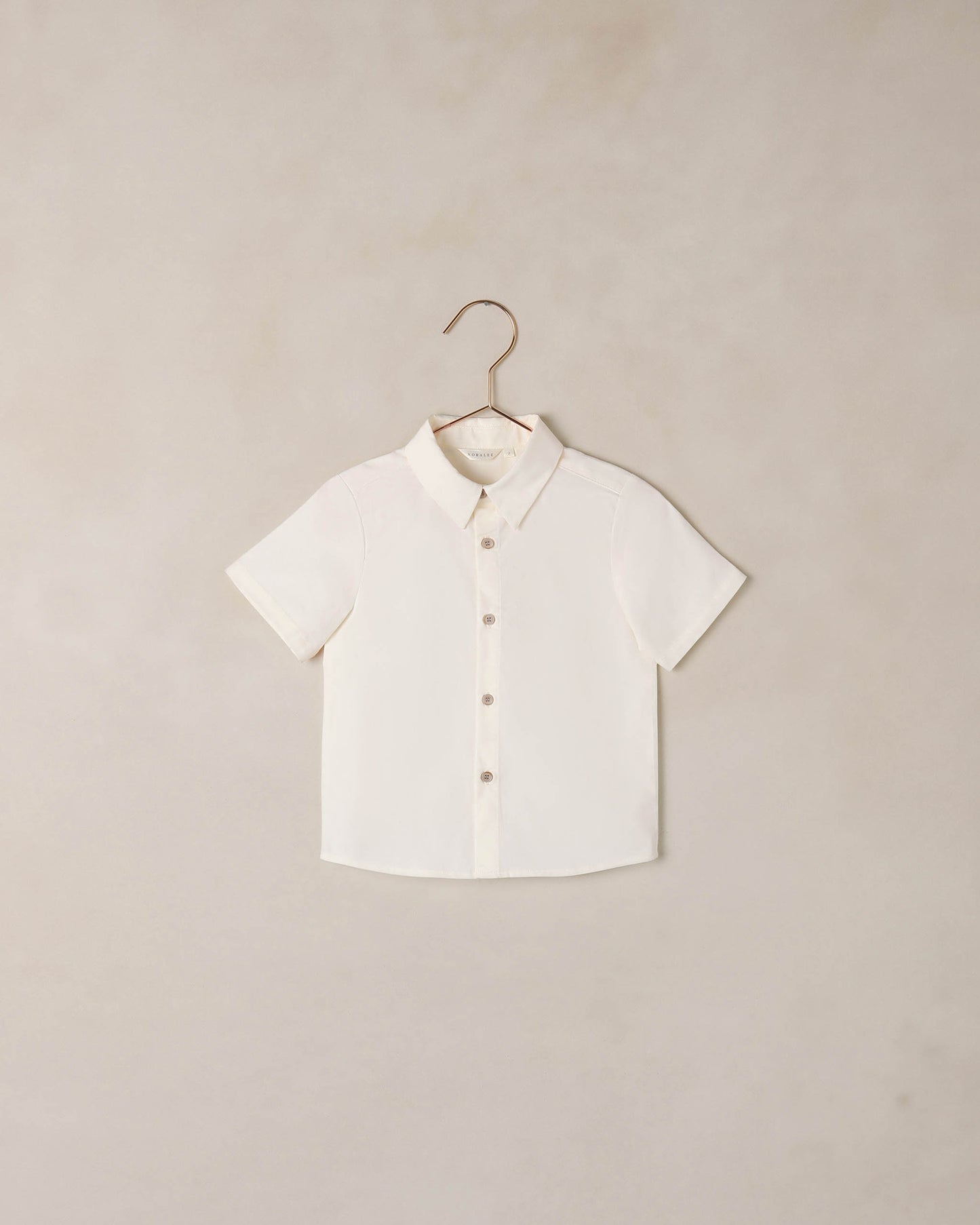 Boy wearing Noralee Atlas shirt in ivory, casual long-sleeve shirt with button details, front view.