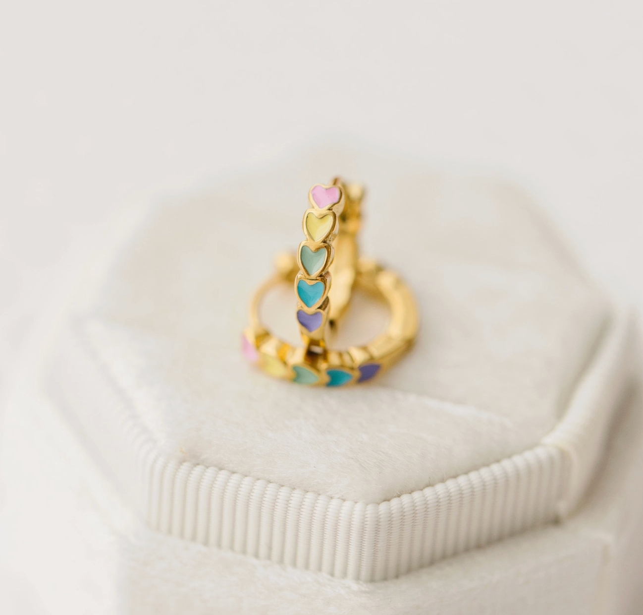 Rainbow Heart Hypoallergenic Huggies earrings by Pierced Co, featuring colorful heart-shaped studs for sensitive ears.
