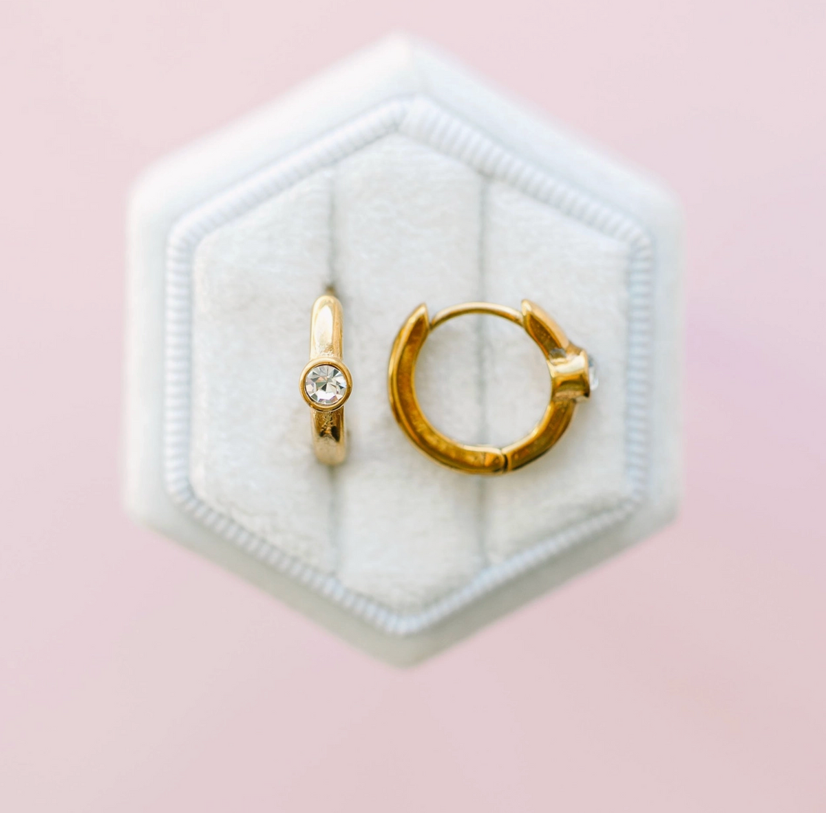 Single diamond huggie earrings by Pierced Co featuring sparkling diamond accents on gold hoops.