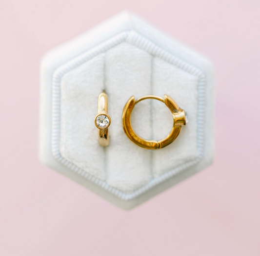Single diamond huggie earrings by Pierced Co featuring a small, elegant gold hoop with a sparkling diamond accent.