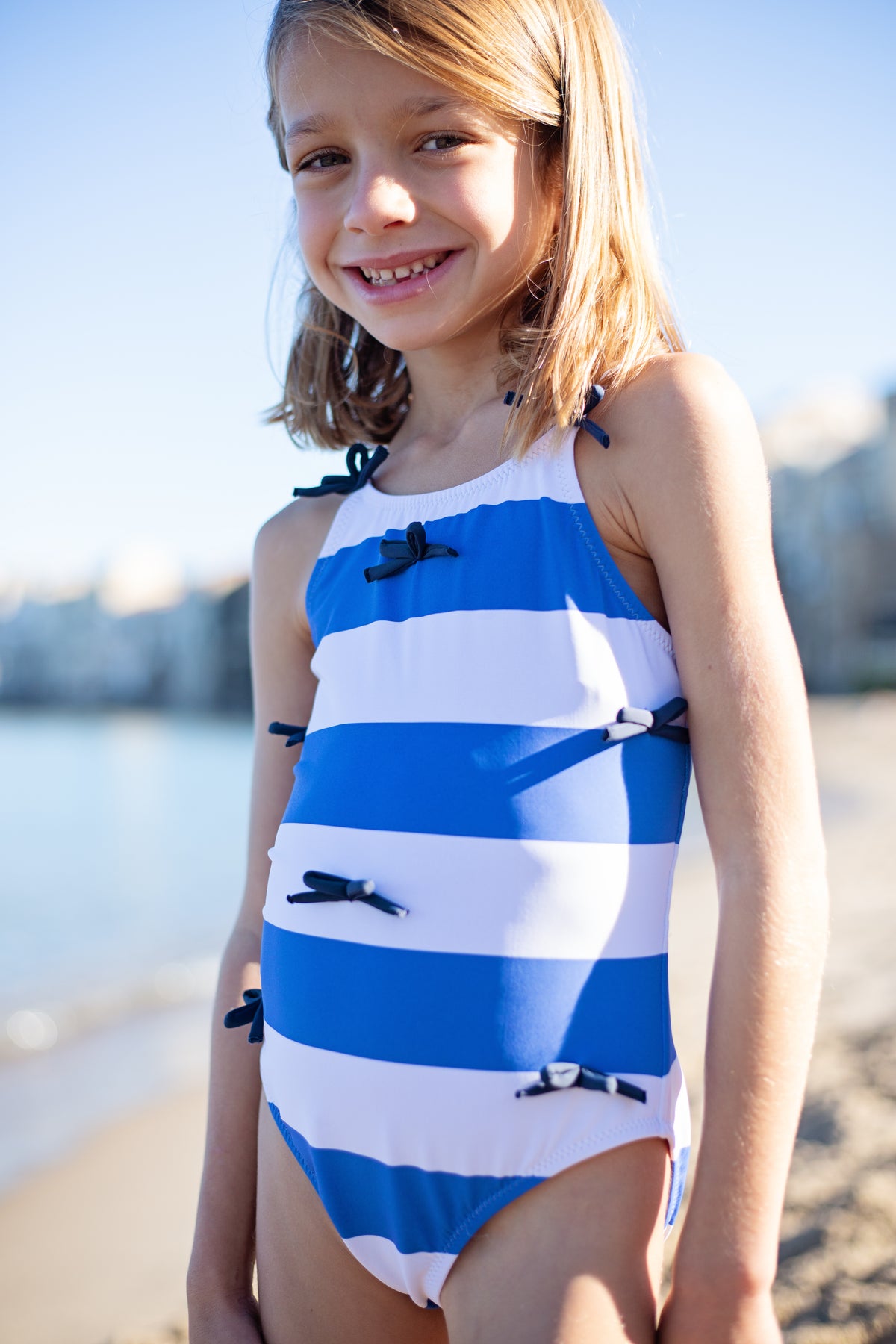 Girls' Lottie Bow Suit by Pink Chicken featuring wide blue stripe fabric, with a bow detail and comfortable summer style.