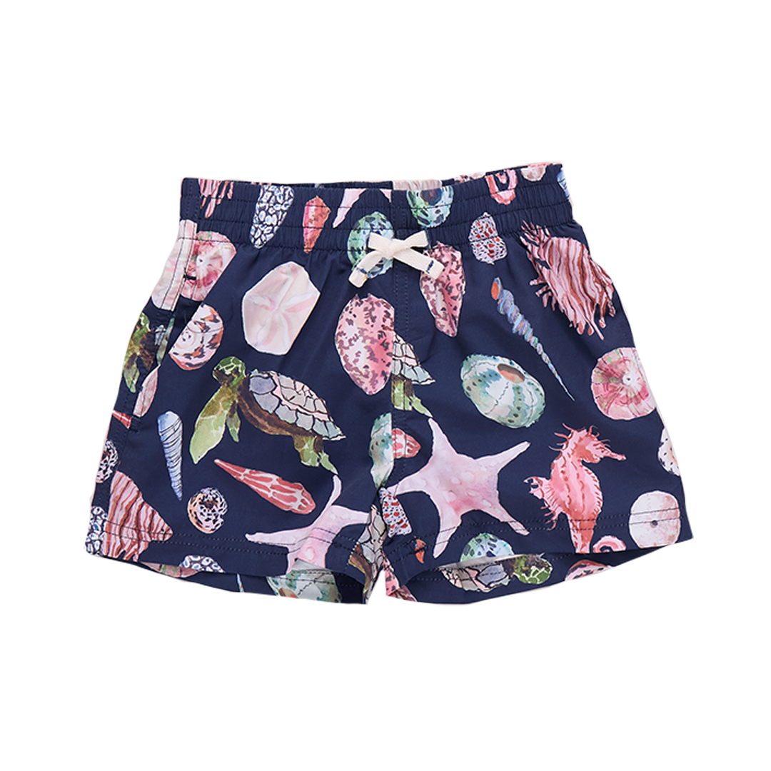 Baby boy wearing Pink Chicken navy swim trunks with watercolor shell pattern, front view of boys' swim trunk.