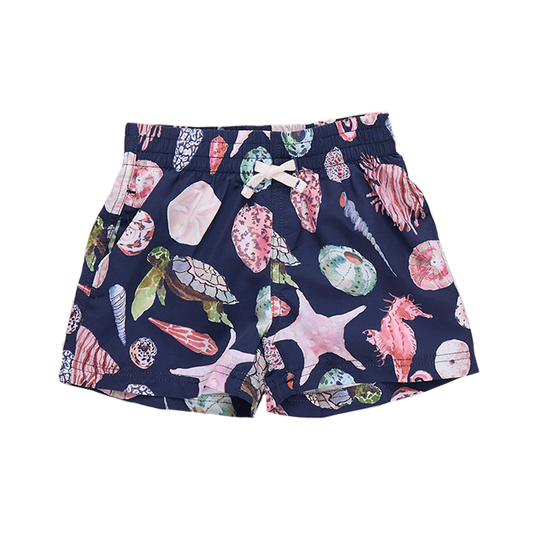 Baby boy wearing Pink Chicken navy swim trunks with watercolor shell pattern, front view of boys' swim trunk.