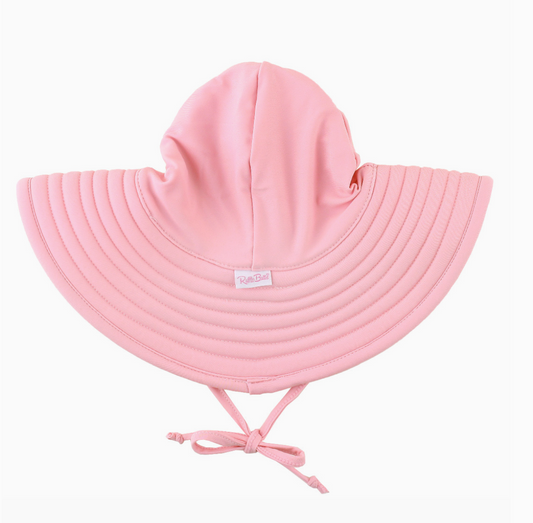 Girls pink swim hat by Ruffle Butts featuring a soft fabric brim and playful ruffle detail, perfect for sunny days at the pool.