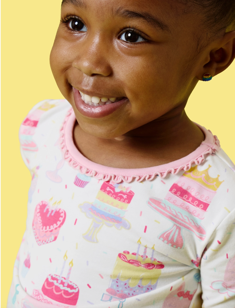 Girls birthday cake pajama set by Ruffle Butts, featuring colorful cake print and ruffled details for 12-18 months.
