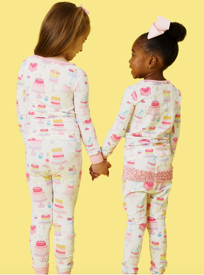 Girls birthday cake pajama set by Ruffle Butts, featuring colorful cake print, soft fabric, and ruffled details for ages 12-18 months.