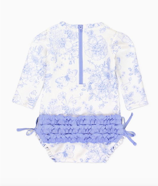 Baby girl in a periwinkle butterfly garden long sleeve rash guard swimsuit by Ruffle Butts, featuring a cute butterfly print and long sleeves.
