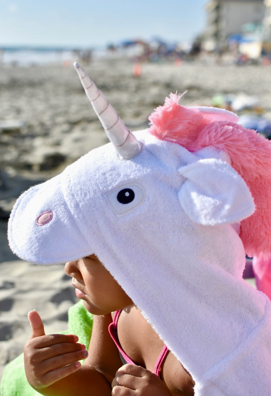 Kids hooded unicorn towel by Yikes Twins featuring colorful unicorn design and soft, absorbent fabric for swimming or bath time.