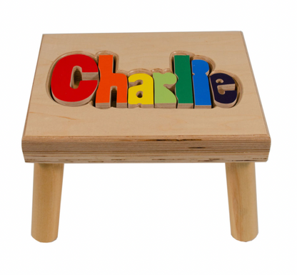 Custom Flora Ottimer Classic Puzzle Name Stool with colorful puzzle piece design and personalized name on a wooden seat.