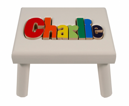 Custom Flora Ottimer classic puzzle name stool with colorful puzzle piece design and personalized name detail.