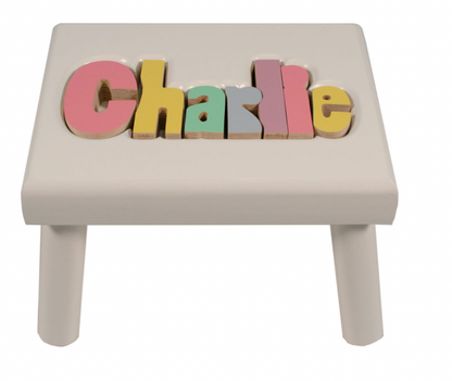 Custom Flora Ottimer Classic Puzzle Name Stool with colorful puzzle piece design and personalized name engraving.