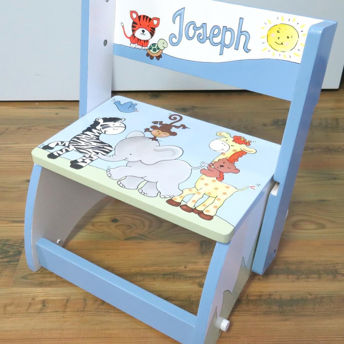 Hand-painted flip stool by Flora Ottimer, featuring vibrant custom floral artwork on wooden seat and flip-up legs.