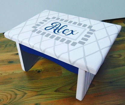 Hand-painted custom foot stool by Flora Ottimer featuring colorful, artistic design on wooden surface.