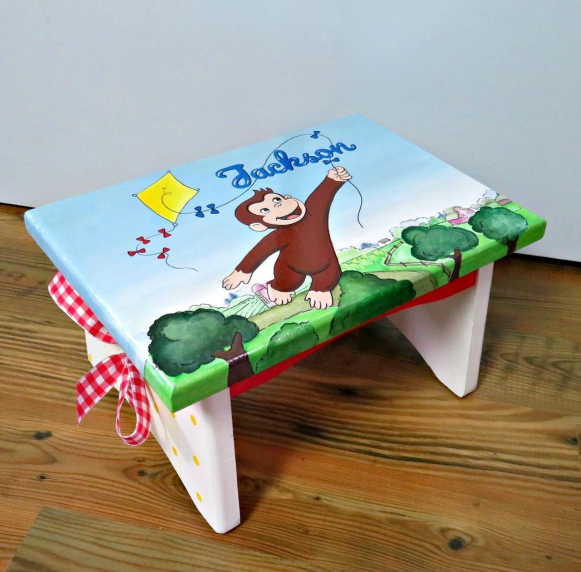 Hand-painted custom foot stool by Flora Ottimer, featuring vibrant floral artwork and a wooden base.
