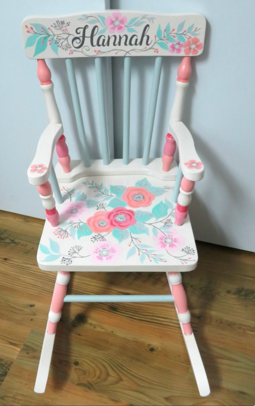 Hand-painted wooden rocking chair by Flora Ottimer featuring intricate floral artwork and a comfortable curved design.