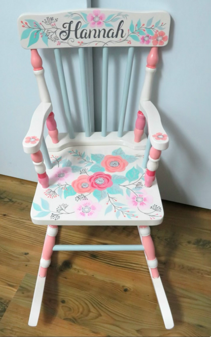 Hand-painted wooden rocking chair by Flora Ottimer featuring intricate floral artwork and a comfortable curved design.