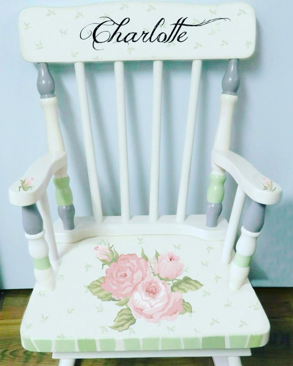 Hand-painted wooden rocking chair by Flora Ottimer, showcasing colorful floral artwork on a classic design.